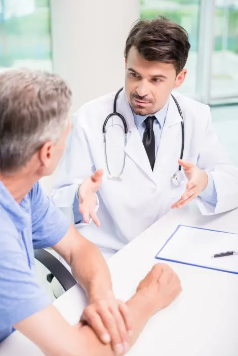 Male doctor talking with patient seriously at clinic.